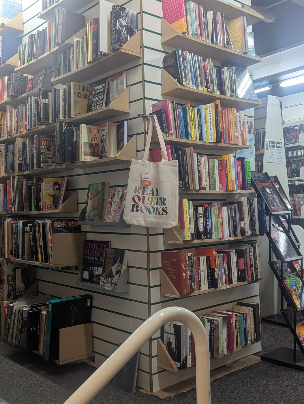 A corner of tall shelving with a Read Our Books tote bag